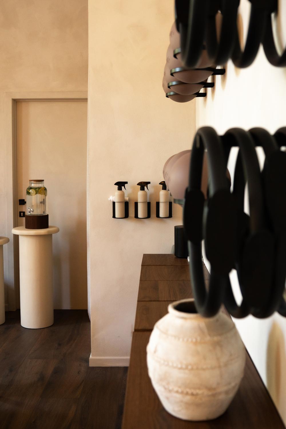 Studio corner with water dispenser, pilates rings and a clay vase